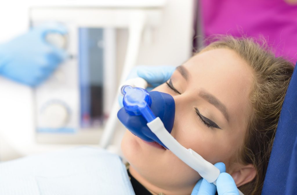 woman with her eyes clothes receiving inhaled sedation through a blue mask