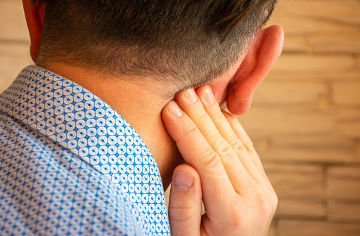 Man touching sore neck with right hand