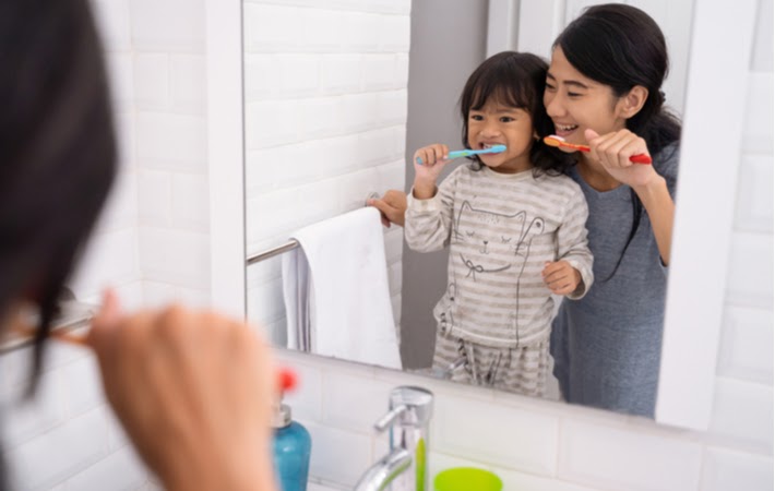 Mother and daughter brushing their teeth before bed.