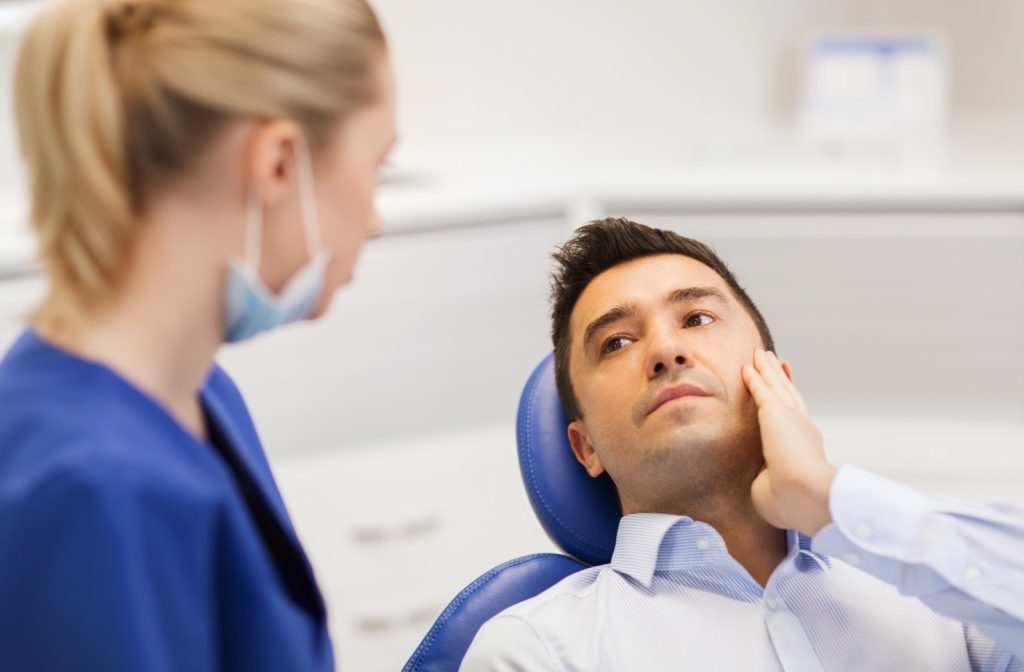 Young man at dentist office explaining tooth pain to his doctor.