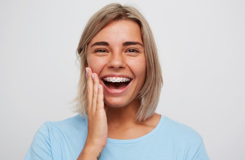 Happy young woman touching her face as she shows off her braces