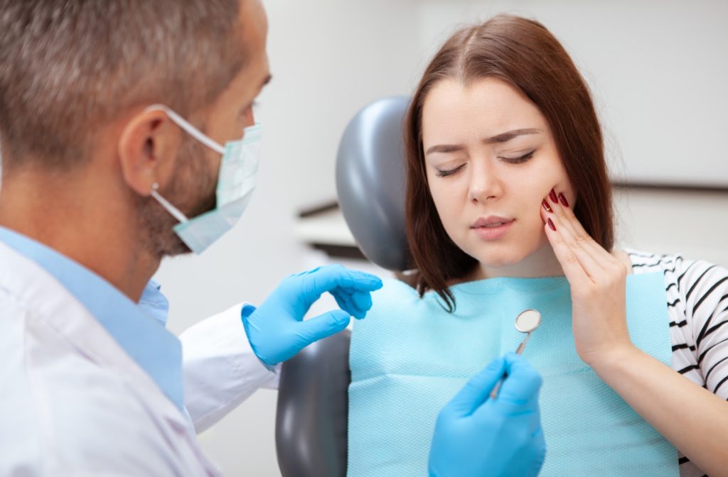 Young woman touching her face to show pain in teeth to her dentist