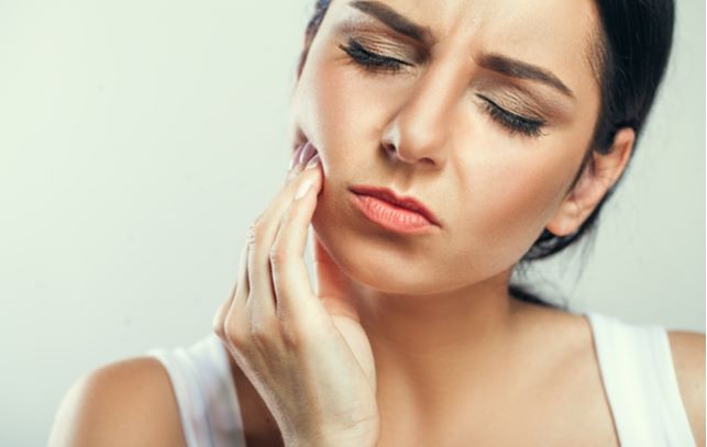 Young women touching teeth mouth due to tooth pain caused by wisdom teeth.