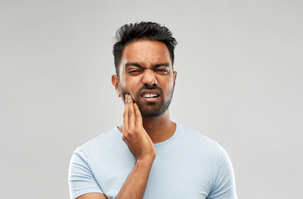 Man experiencing toothache and touching face area where it hurts