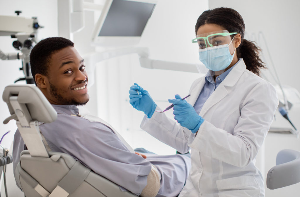 Happy man at dental office getting dental cleaning from hygienist