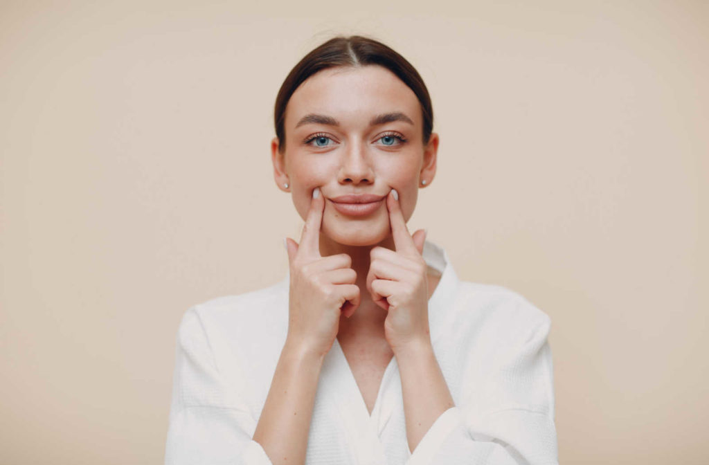 A woman gentle massaging her lip and jaw area to help reduce the numbness caused by dental freezing.