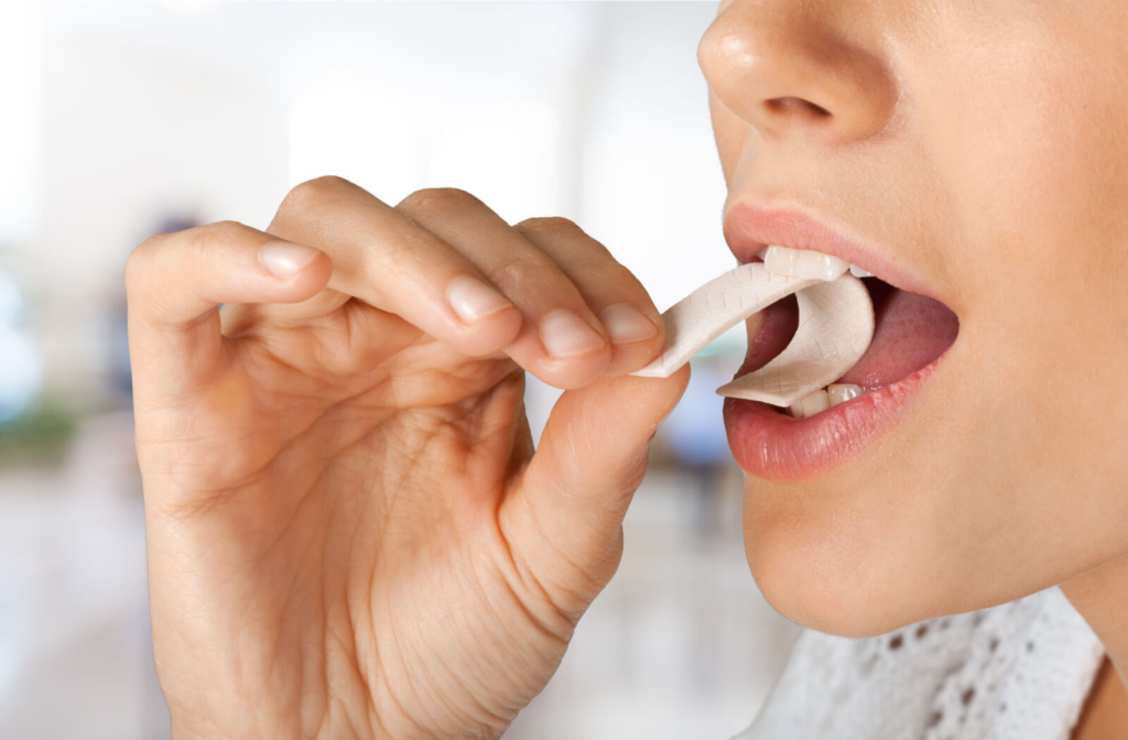 A close-up of a woman chewing a piece of gum with her mouth open.