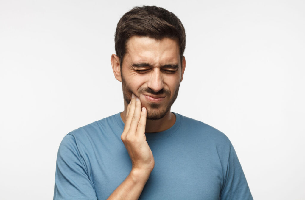 A man suffering from a toothache holds his right cheek with his right hand.