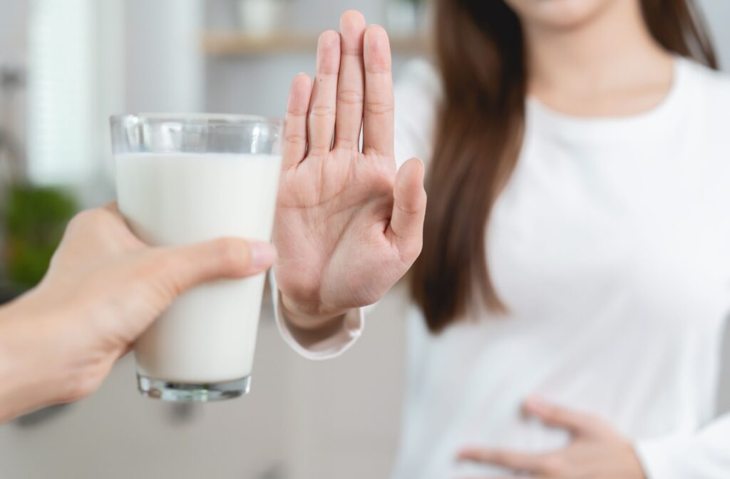 A woman raising her hand to reject a glass of milk.