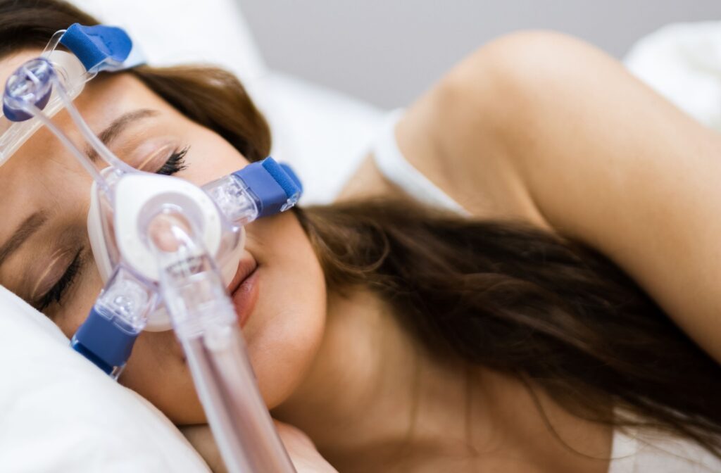 A woman asleep in her bed, wearing a CPAP machine.