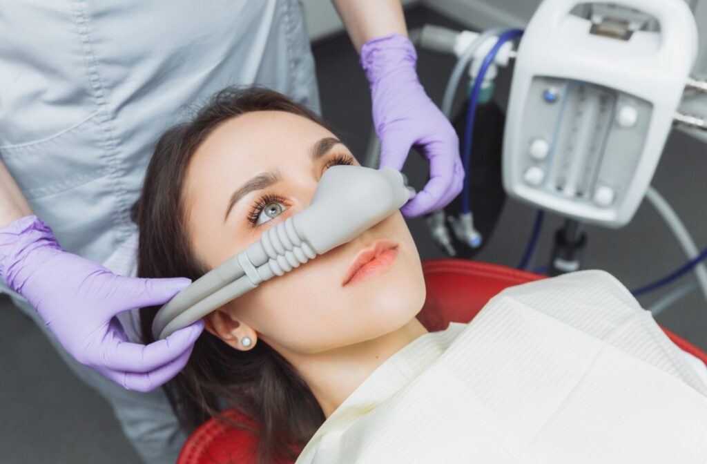 A dentist places an inhalation sedative mask on a patient for a minimal sedation procedure