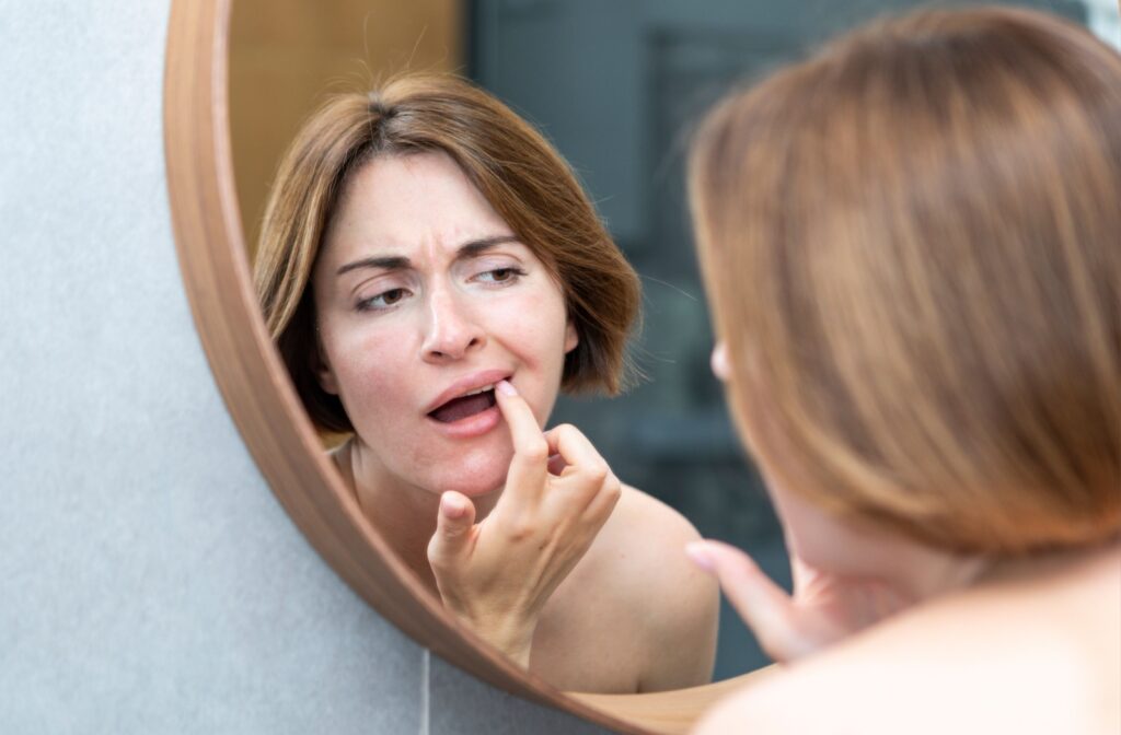 Someone checks their uneven teeth in a mirror.