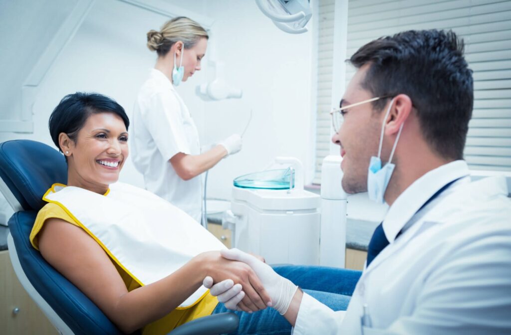 Dentist shaking hands with a smiling patient during a consultation about missing tooth replacement options
